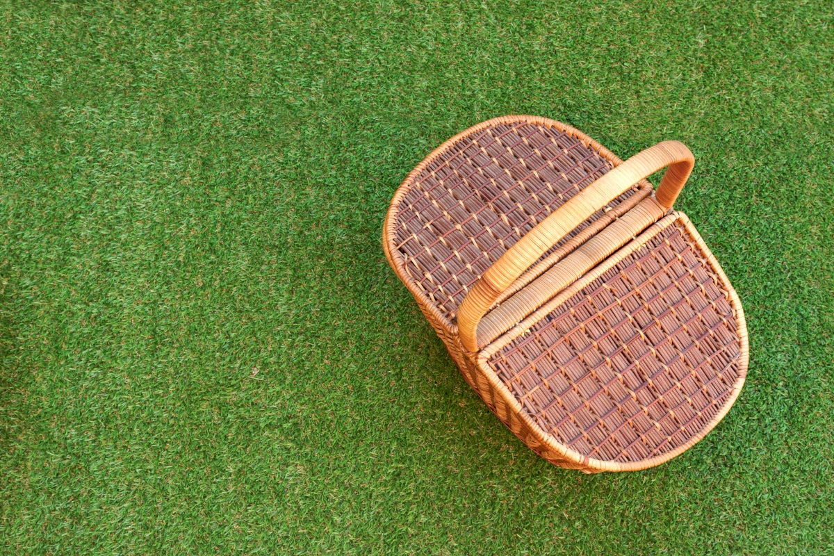 Cesta de comida con snacks para picnic encima del césped