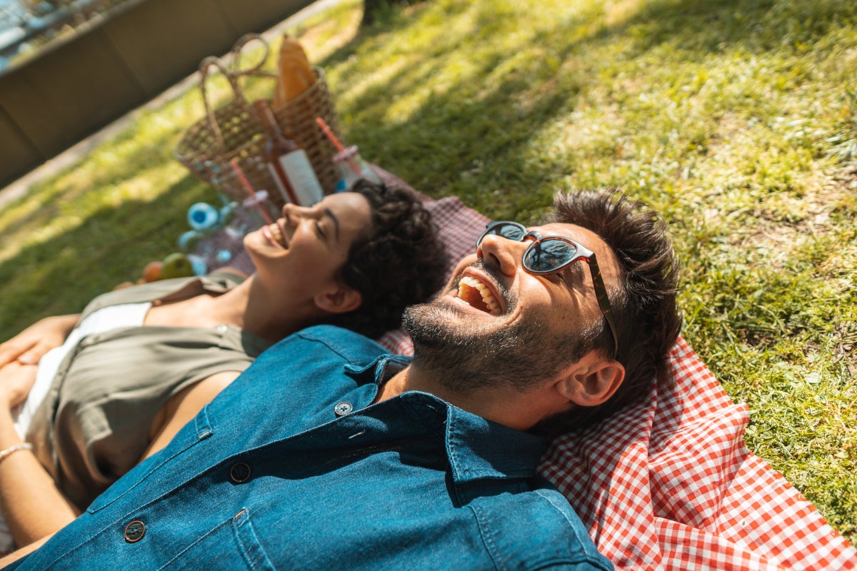 Hombre y mujer acostados en el césped disfrutando de un picnic