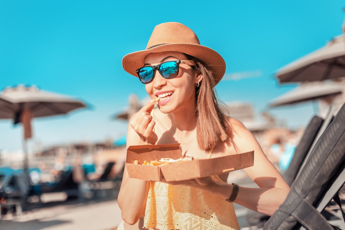 Mujer comiendo en un picnic en la playa