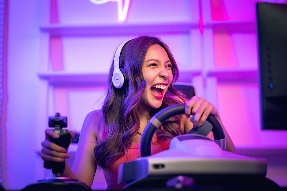 Mujer sonriendo mientras juega un videojuego siendo streamer