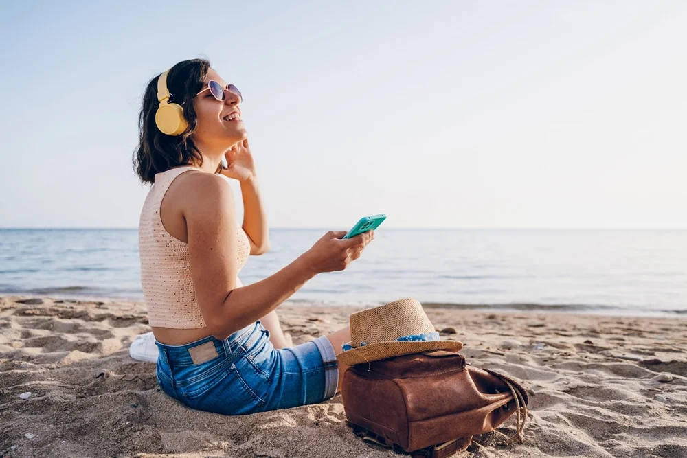 Mujer en la playa escuchando su playlist de música tropical