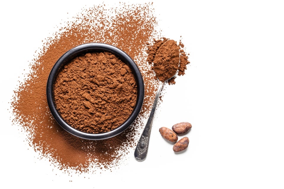 Cocoa en polvo en una taza al lado una cuchara
