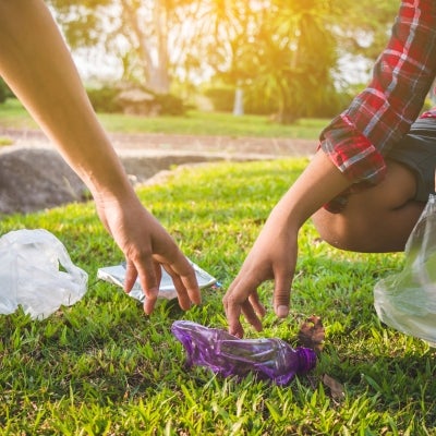 manos de un hombre y una mujer recogiendo botellas plásticas