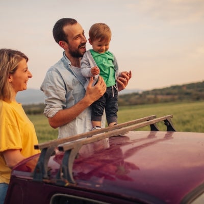 Mujer hombre y niño viendo el paisaje del viaje al lado del carro.