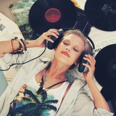 Mujer acostada encima de unos discos con sus audífonos escuchando música