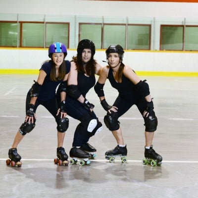Tres mujeres que practican Roller Derby con su equipamiento